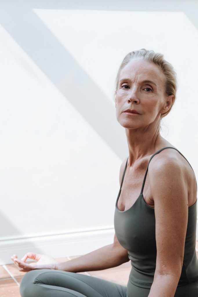 Serene senior woman practicing yoga indoors with natural light.